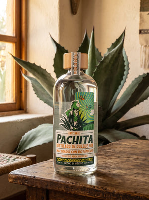 Botella de Pachita Gin, destilado de pulque macerado con botánicos, 750 mL, sobre mesa de madera con maguey salmiana
